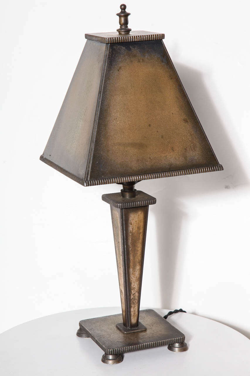 Early 20th Century Arts and Crafts Bronze Table Lamp. Desk Lamp. Bedside Lamp. Library Lamp. Featuring an accentuated triangular bronze stem, vertically incised bronze pyramidal shade on footed 5.25D square bronze base with bronze finial. Original