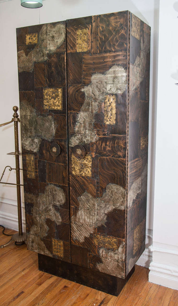 A vintage tall metal patchwork bar, cabinet, or wardrobe with double doors designed by Paul Evans for Directional .  The cabinet is on a pedestal and is part of the patchwork series in which sheets of metals such as copper, bronze, and pewter were