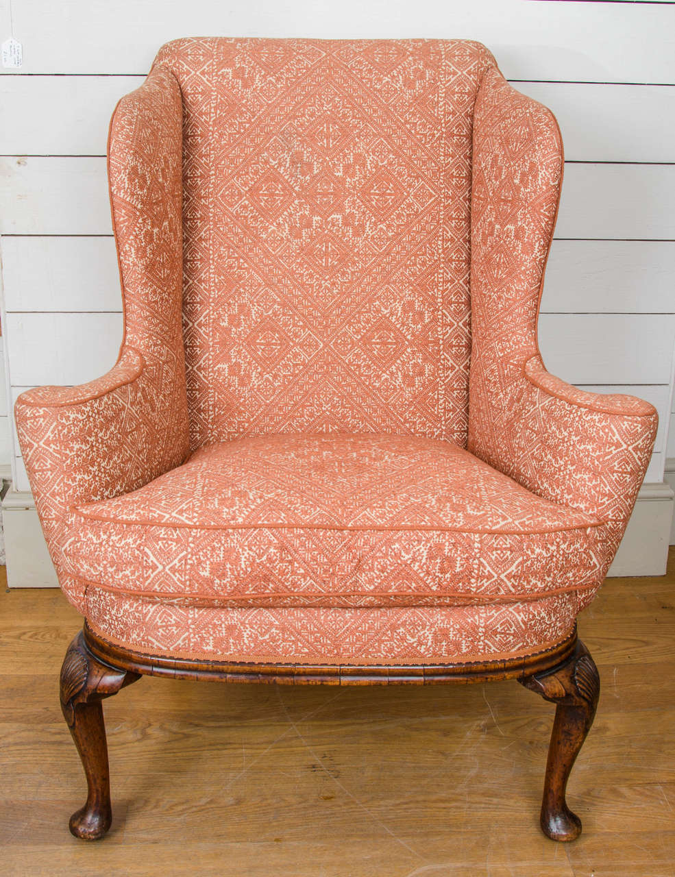 A George I walnut wingback chair with scalloped side above a plain veneered frieze with shell motif to the shoulder on cabriole legs terminating in pad foot.
English, circa 1720