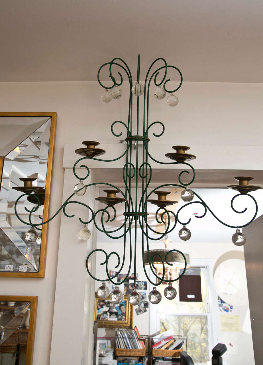 A large-scale candle sconce with brass candleholders. Each dark green painted wire arm has a lovely glass ball hanging. Inquire with us for the option to electrify.