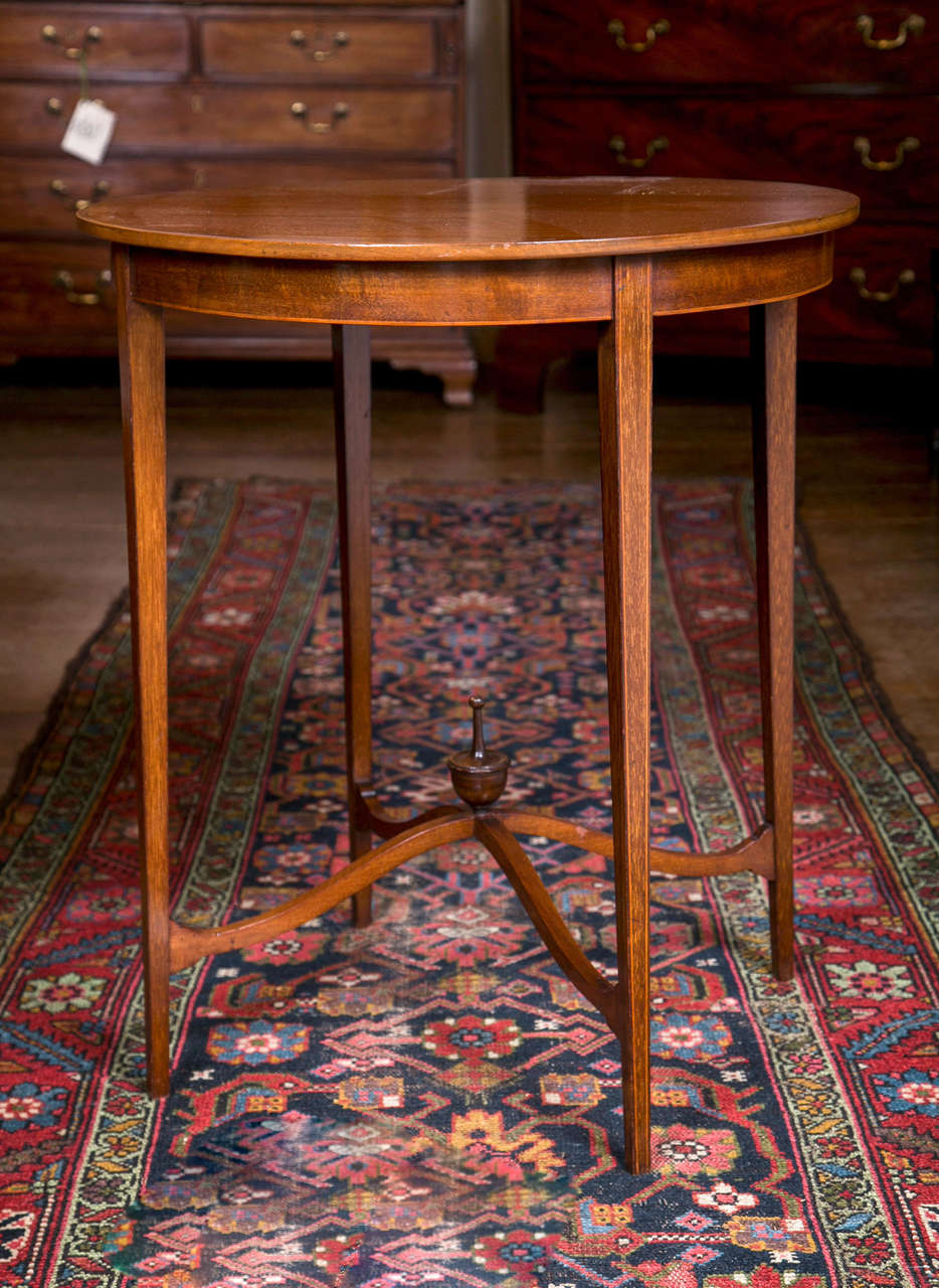 An Edwardian, circular tea table with string inlay and supported by narrow, tapered legs joined by delicate, curved stretchers that meet at a central urn finial.