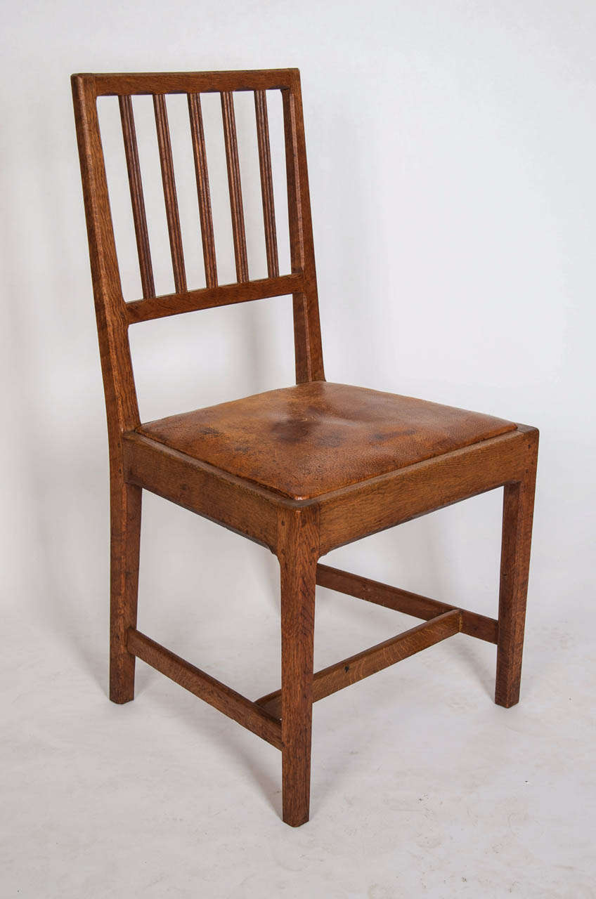 These sturdy oak chairs (2 carvers, 4 singles) are design Numbers 295 and 296, designed by Sir Gordon Russell in 1925 and these examples made in the Russell Workshops, Broadway, England in about 1929. Each chair bears the original Russell Workshops