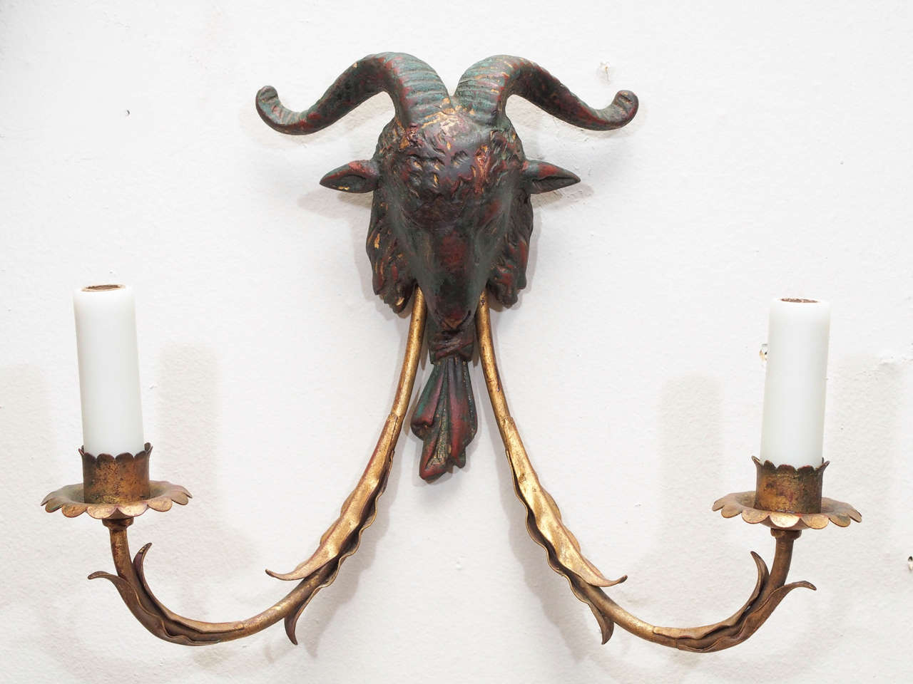 A pair of two-arm wall lights, the arms, sheathed with sinuous leaves, supported by a ram's head. Heads of resin. Produced by Palladio, the Palladio sticker dated 