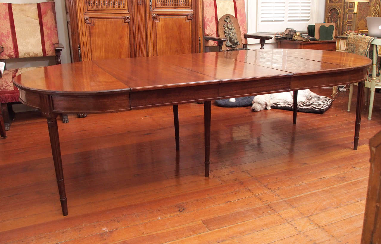 A handsome, mahogany dining table with tapered and fluted legs and a well molded apron. This 19th century table has been updated with two leaves and the legs have been extended. Beautiful, rich color and elegant styling.