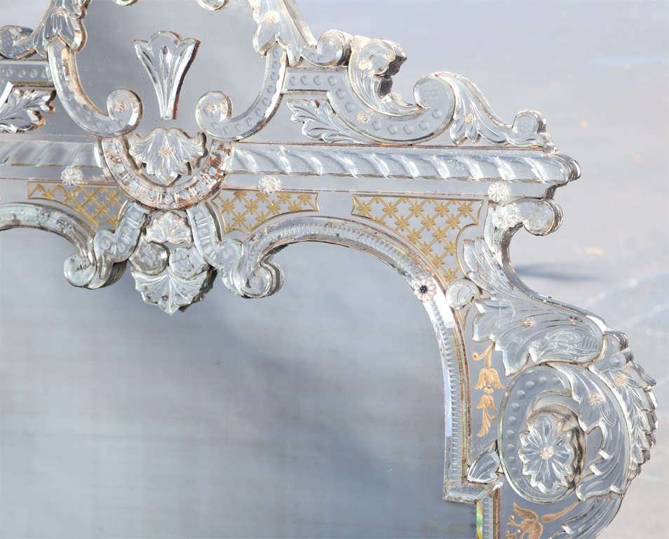 Spectacular mirror, of grand scale, in baroque taste, its impressive cresting and frame of handcut curved beveled and etched Venetian glass; ornately decorated with C-scrolls, beading, rosettes, ribbons and gold latticework.