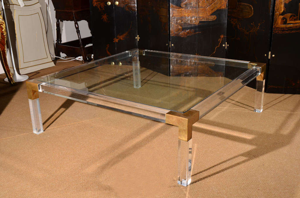 a large square coffee table of lucite with copper accenting the corners