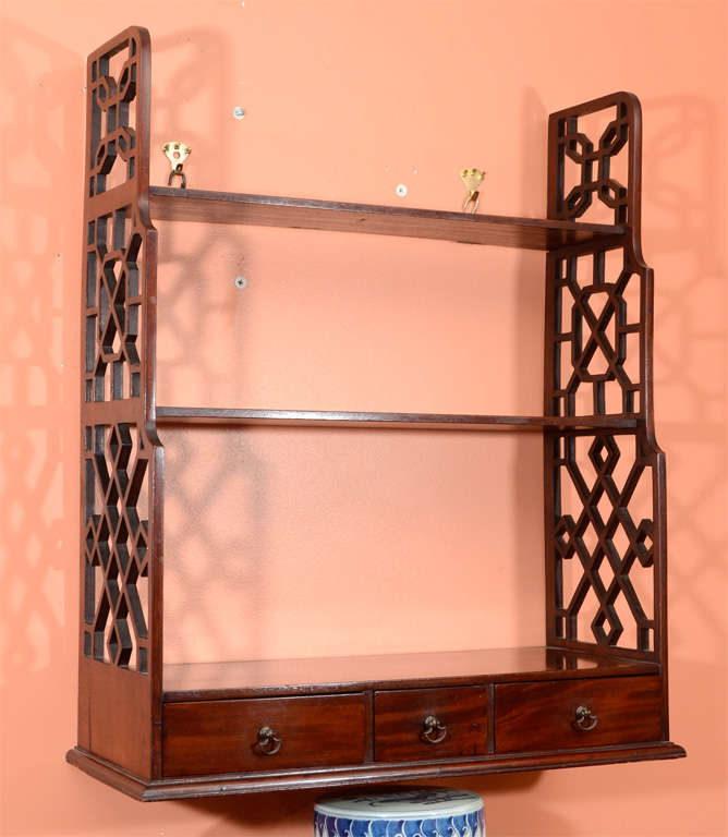 Pair of George III mahogany three-tier hanging shelves with openwork carved supports, stepped shelves and three drawers.