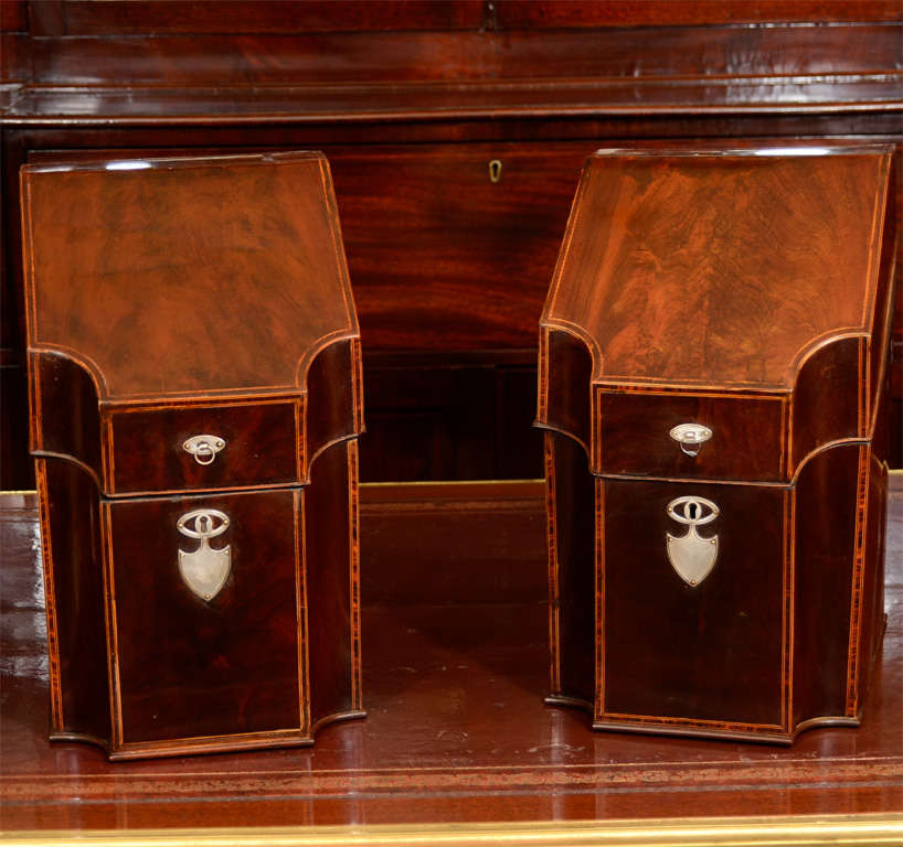 Une paire inhabituelle de carafes à décanter en acajou de George III, à dessus oblique et bordées de buis, avec des intérieurs ajustés et des montures en argent.