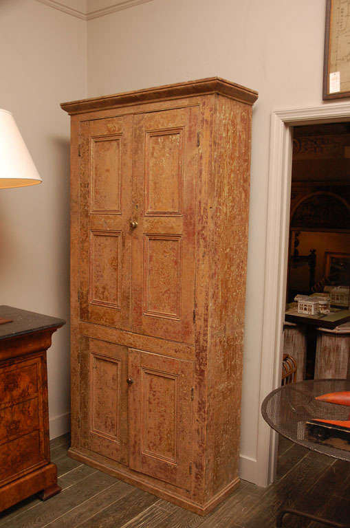 A tall cabinet or linen press with a projecting cornice top over upper and lower panel doors on a plinth base.