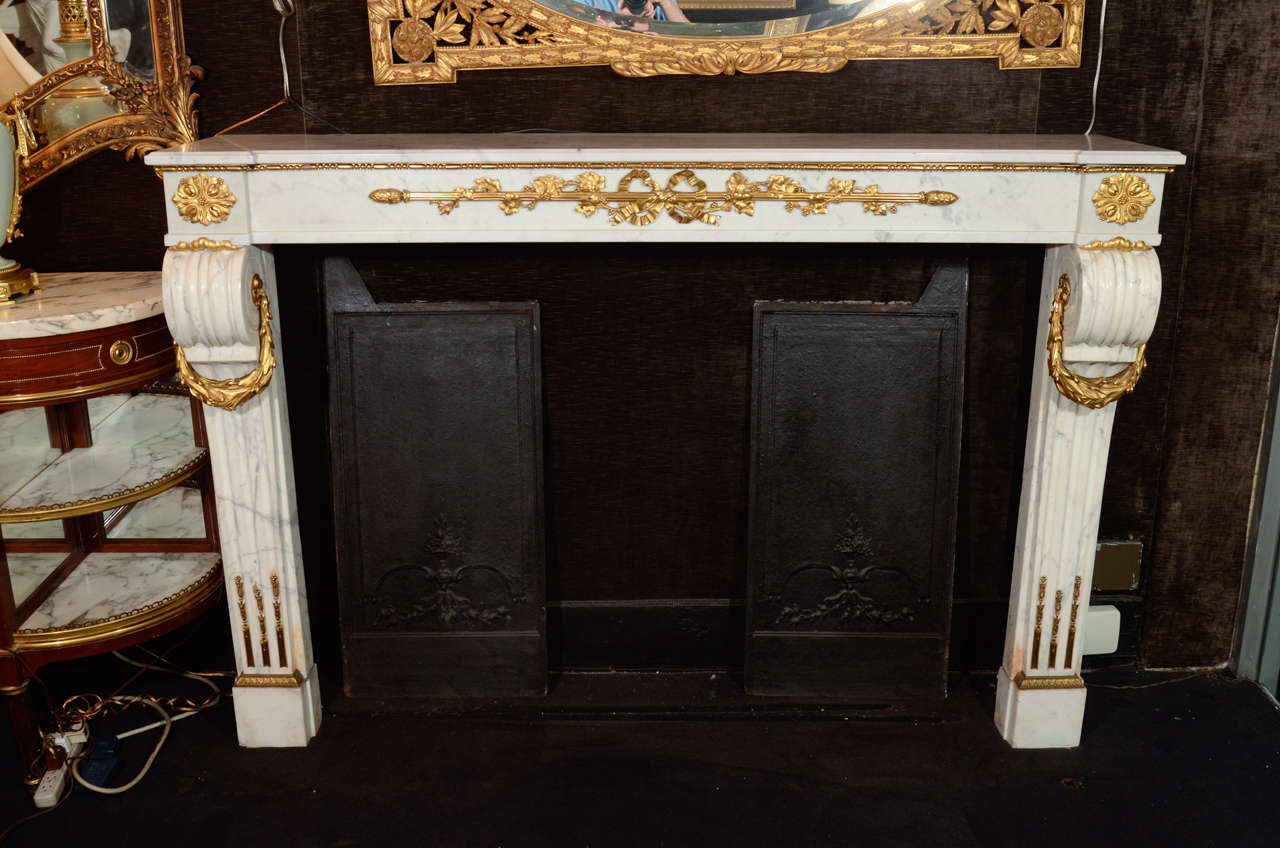 Spettacolare grande caminetto in stile Luigi XVI francese del XIX secolo, in bronzo ormolu e marmo bianco di carrara intagliato a mano, di squisita fattura. Il ripiano rettangolare in marmo bianco con angoli squadrati e affilati poggia su gambe