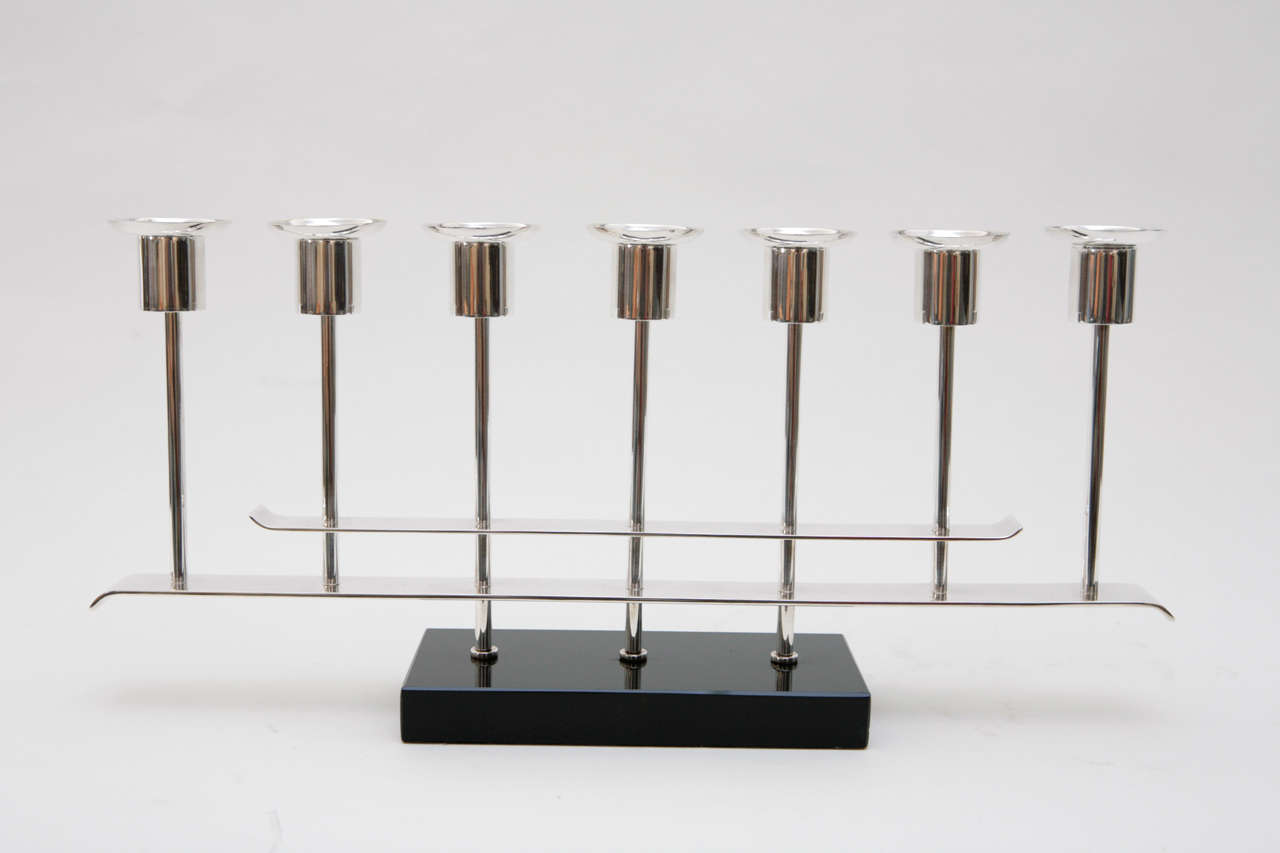 A striking and stylish pair of Art Deco silver plate candelabras, designed to hold seven tapers, on a black glass base. The bobeches are removable.