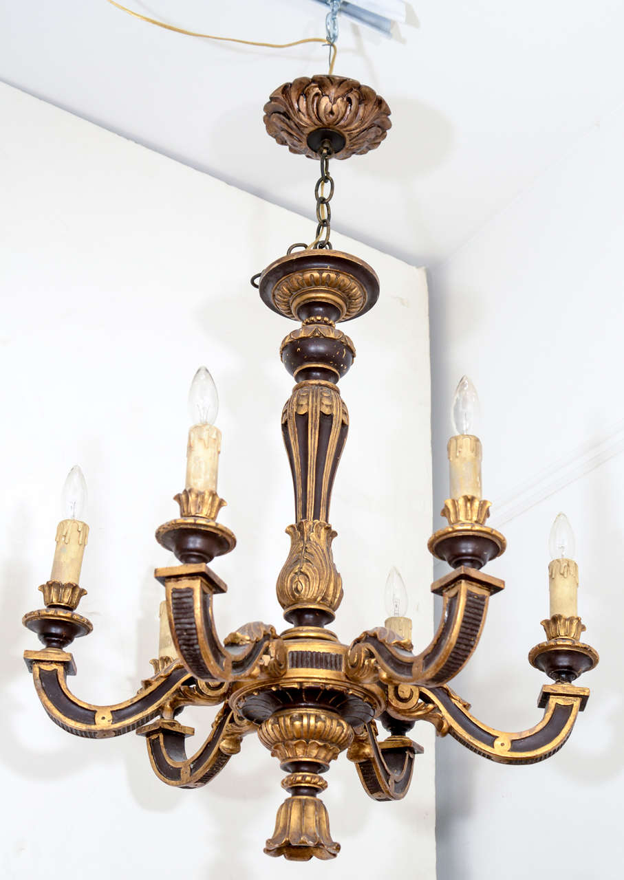 Carved in the 1920s with a distinct Baroque vibe, this six armed fixture with candles, puts a light hearted, early 20th century spin on banquets, dungeons and wine cellars, to name a few applications.