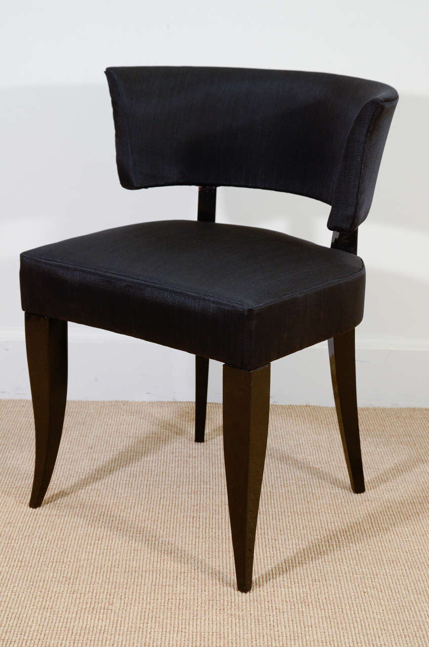 The upholstered seat supported by tapering slightly curved black lacquered legs, with a curved upholstered back.