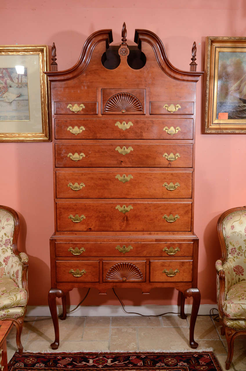A fine American Cherry Highboy chest with a scroll top and carved shells raised on cabriole legs and pad feet.
