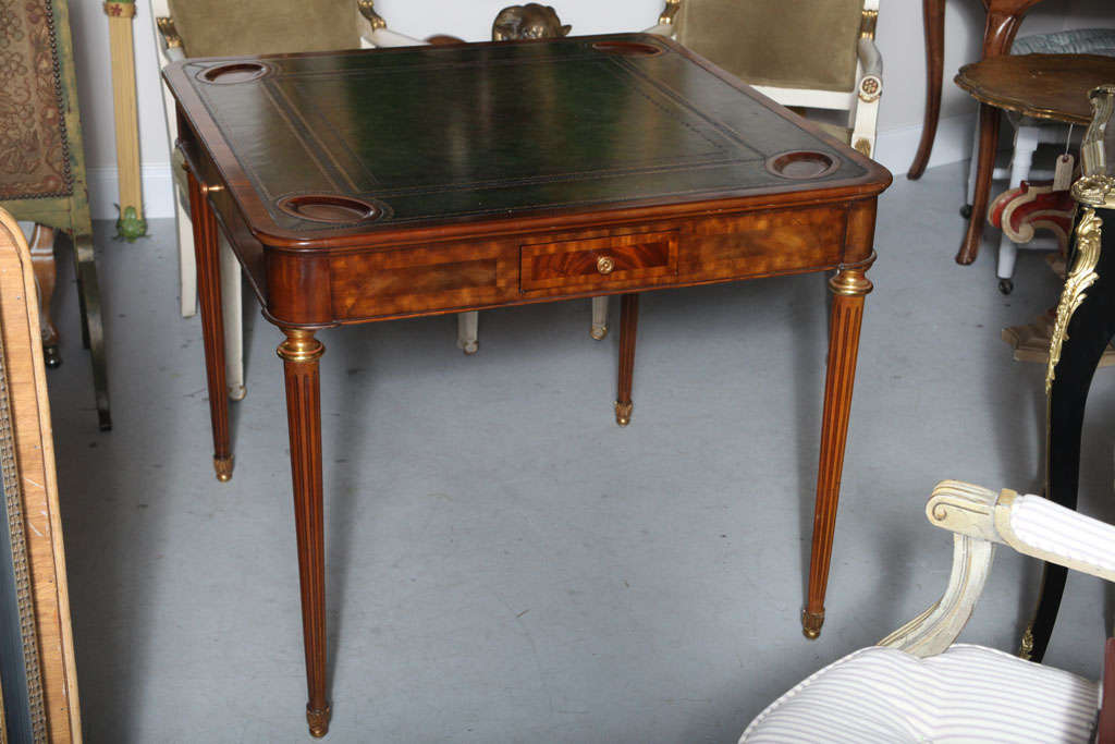 Handsome wood veneer table with embossed dark green leather top and beautiful details with four drawers.