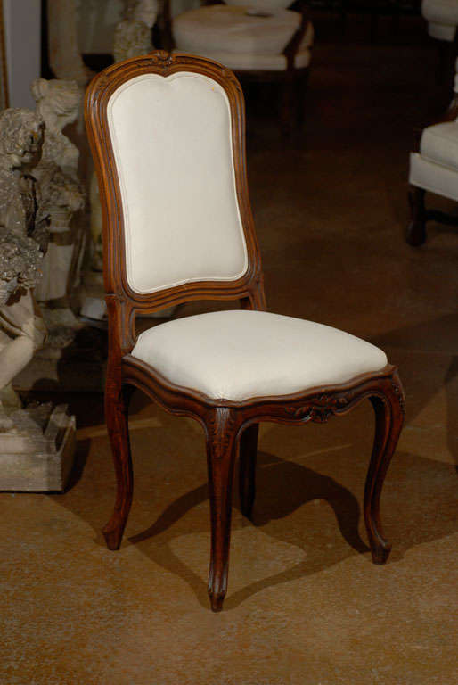 A set of six French Louis XV style walnut dining room side chairs from the 19th century, with scalloped apron, cabriole legs and new upholstery. Each of this set of French Louis XV style chairs features a delicately carved, slightly slanted back,