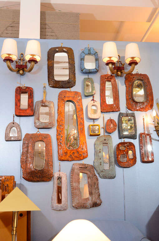 Group of nineteen roughly shaped enameled glazed ceramic frame mirrors, in various colors including red/orange, blue, white, yellow and mauve. By Juliette Derel, French 1950s-1970s. Signed to back. Various sizes, the height of largest is 25