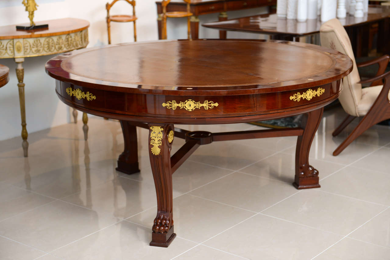 The circular top with leather inset and mahogany banding and mother-of-pearl inlay designating the drawer above eight drawers each with bronze mounts resting on animal form legs terminating with lion paw feet, also with bronze mounts, joined by a