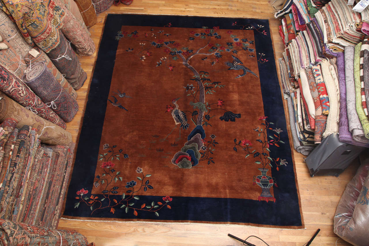 Art Deco wool rug.  China, circa 1920. 

Features a tan center with navy border and a flora/fauna design.