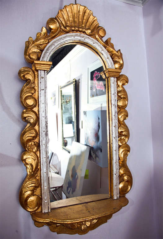 This elegant Baroque style carved silver and gold gilt mirror illuminates its surroundings with graceful taste.