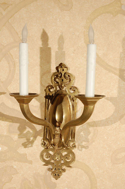 Pair of Brass Two-Light Sconce with Oval Back Plates that are Surrounded by Scrolled Fretwork.  These Were Originally Gas Sconces that Have Been Electrified
