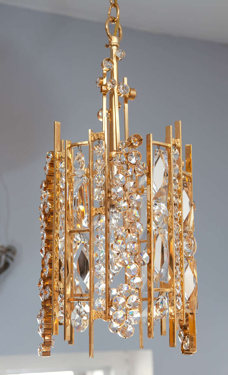 A rare pair of delicate and detailed hanging single light pendants, encrusted with jewel like Austrian crystals, embedded in a gold frame. Simply stunning!