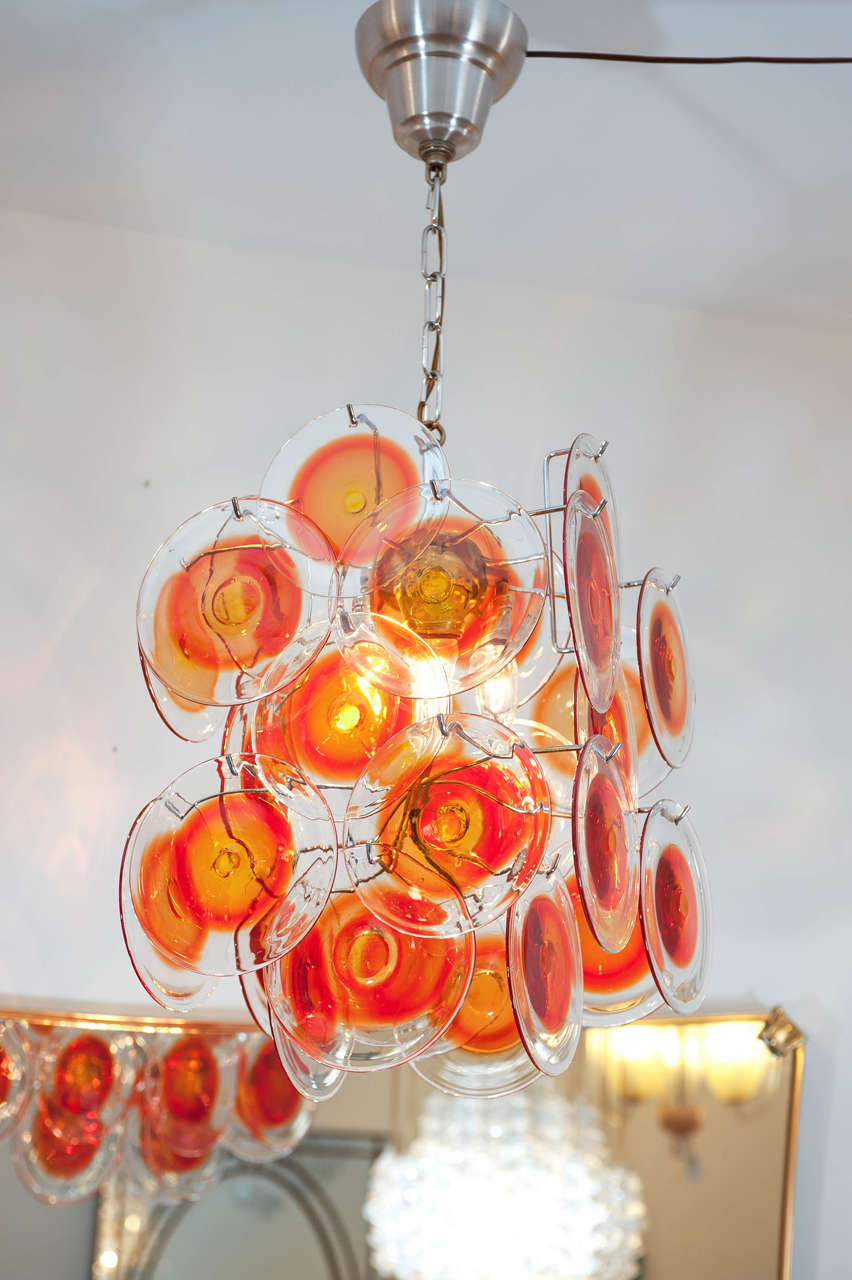 A funky and cool vintage orange glass disc pendant light from Italy. Original brushed steel frame.