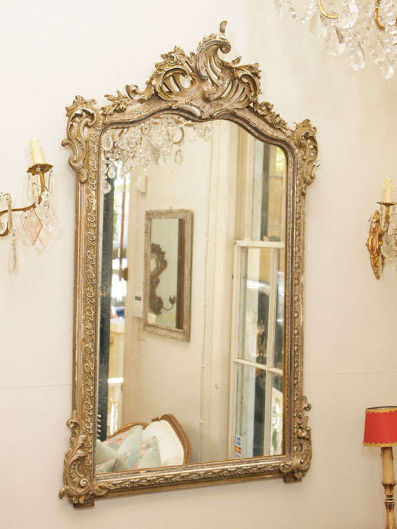 Photos just do not do justice to the beauty of this mirror.  Heavily carved with layers upon layers of old paint, this mirror is a one of kind antique treasure.  Remnants of silver gilding showing through the gustavian grey painted frame.