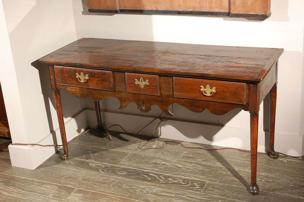 18th century English oak three drawer dresser base or sofa table server with three frieze drawers and a carved apron raised on slender legs with pad feet. Great as a side table, occasional table, small credenza, or sideboard.