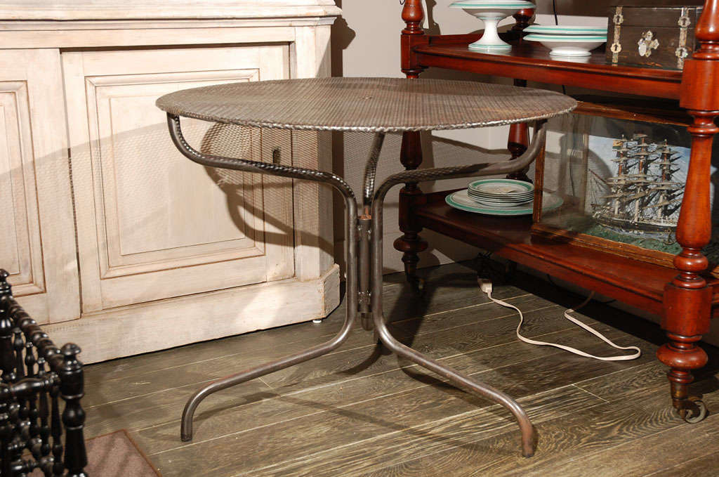 A round open patterned top table with a curved base of three legs