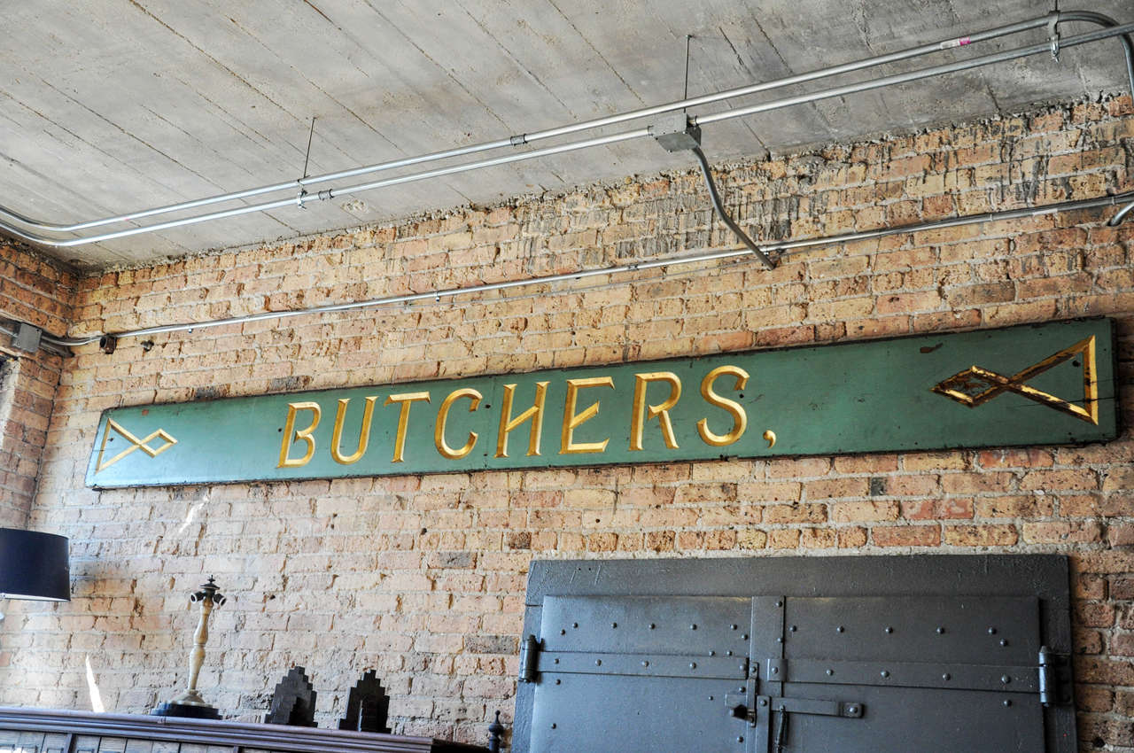 A monumental early 20th century English wooden butcher shop sign with original green paint and gilt painted letters.