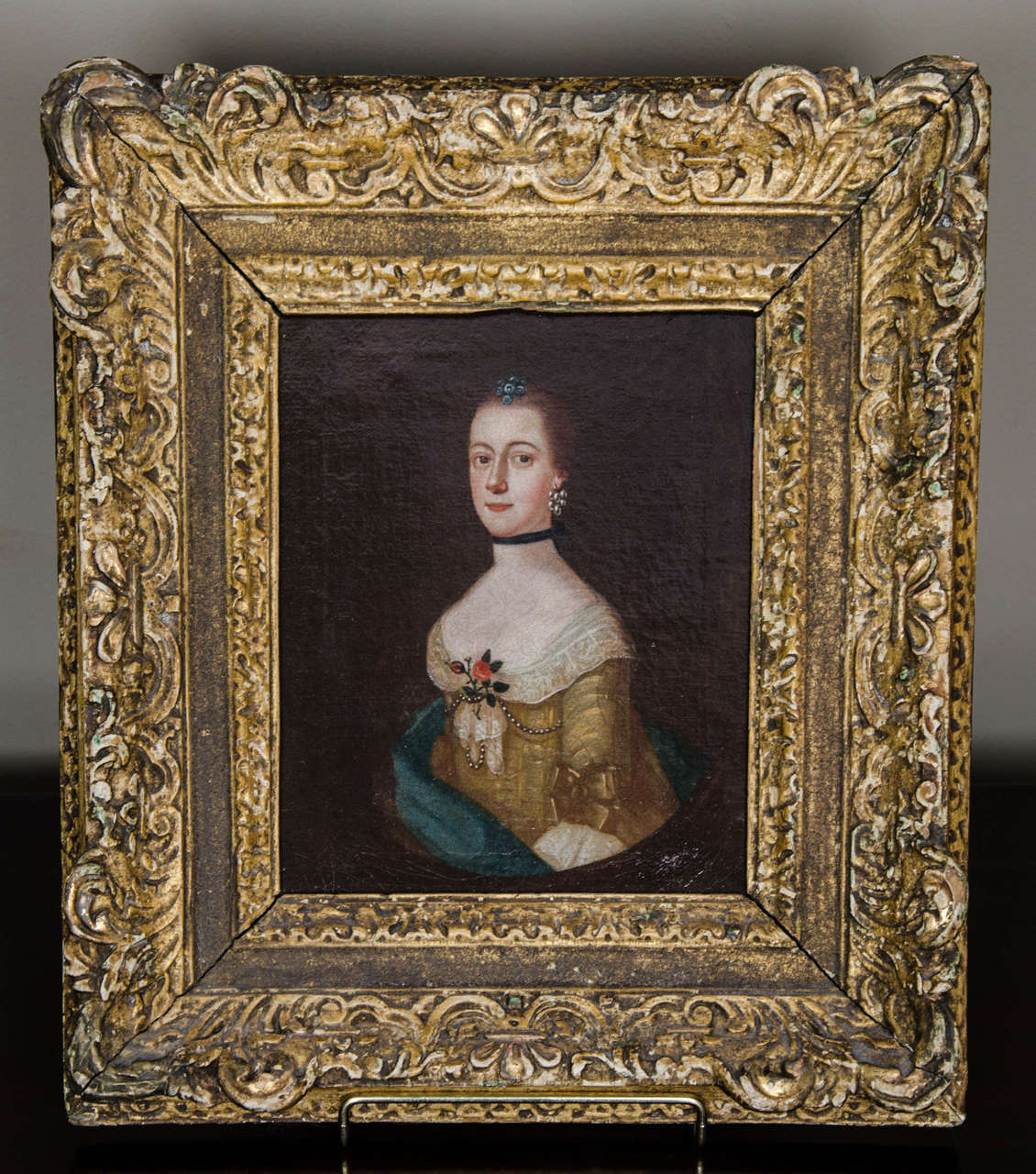 A small Georgian oil portrait of a young lady circa 1730. A very charming small scale oil painting of very unusual size. This is not a miniature but a proper oil painting on canvas in a hand carved and gild frame of the same period. The sitter is