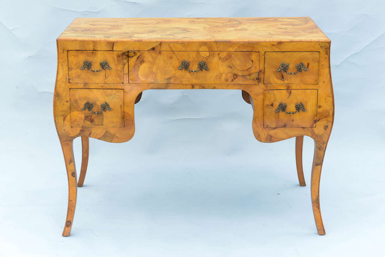 Desk or vanity, in olivewood patchwork veneer surface, having a rectangular top on bombe form base, with five drawers, raised on cabriole legs.