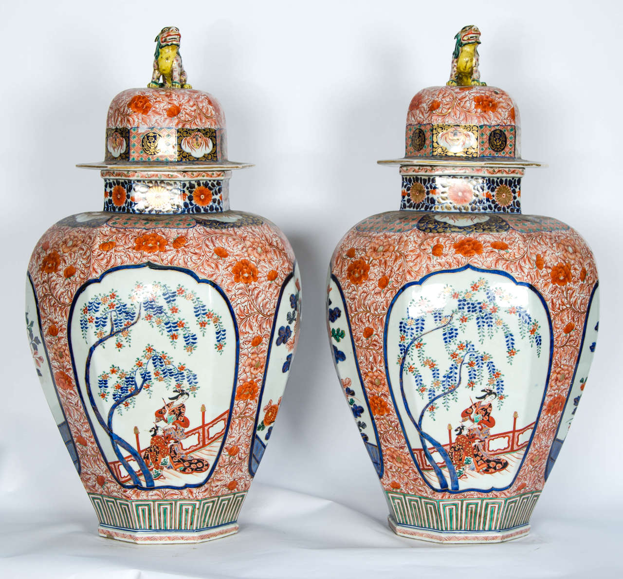 A large and impressive pair of 19th century Japanese Imari lidded vases, having dogs of faux to the lids, hand-painted floral panels and surrounds of wisteria and chrysanthemums.