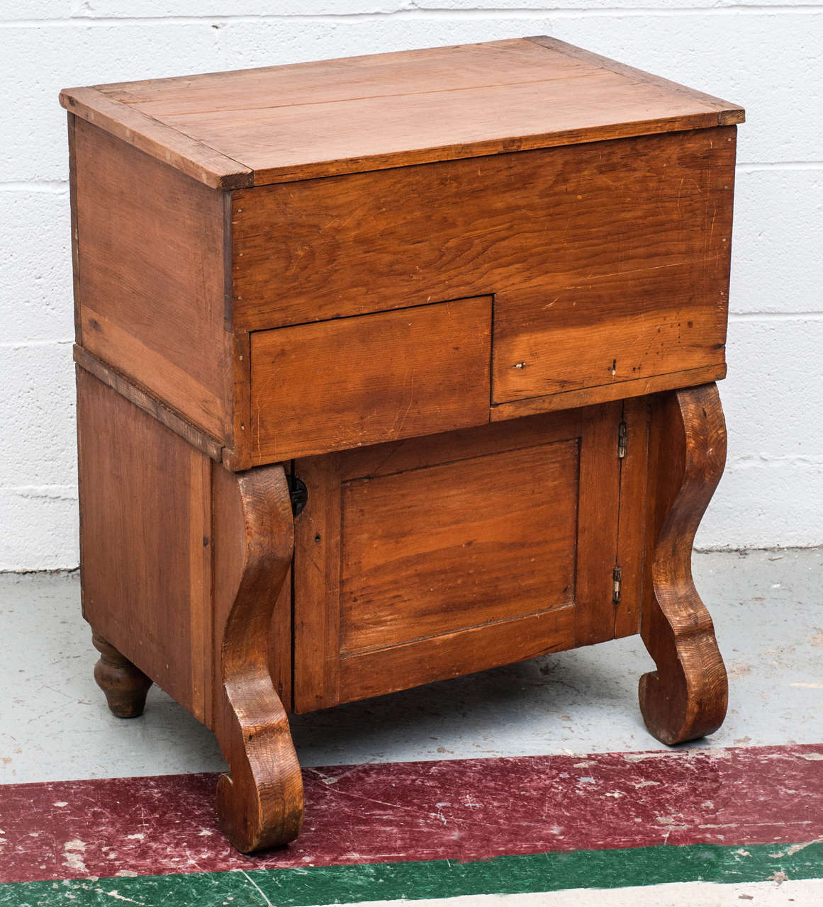 A most unusual small dry sink with lifting top and single drawer to the front, mounted on a single door base with Empire style front legs. Entirely original. Probably from Maine.