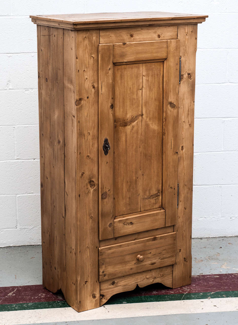 A plain and attractive single panelled door pine cupboard with a single hand-cut dovetailed drawer beneath and a primitive bracket foot.