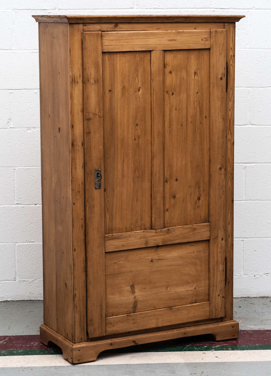 A great little pine storage cupboard, the wide-swinging three panelled door concealing four hand cut dovetailed drawers with painted bin pulls with storage space above and beneath. Exposed dovetails to the top and bracket feet.