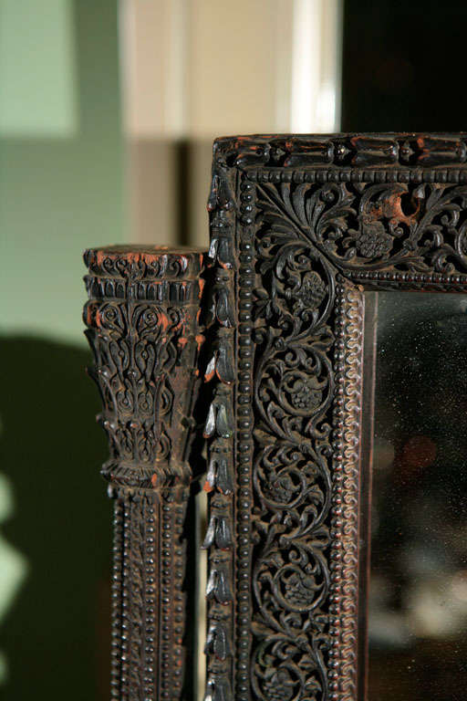 19th C. intricately carved ebonized wood dressing mirror. This old exotic piece has a gimbled mirror, natural ghosting, mounted on a small shelf with two dovetailed drawers. This piece is all hand made, and has a mysterious ancient presence in