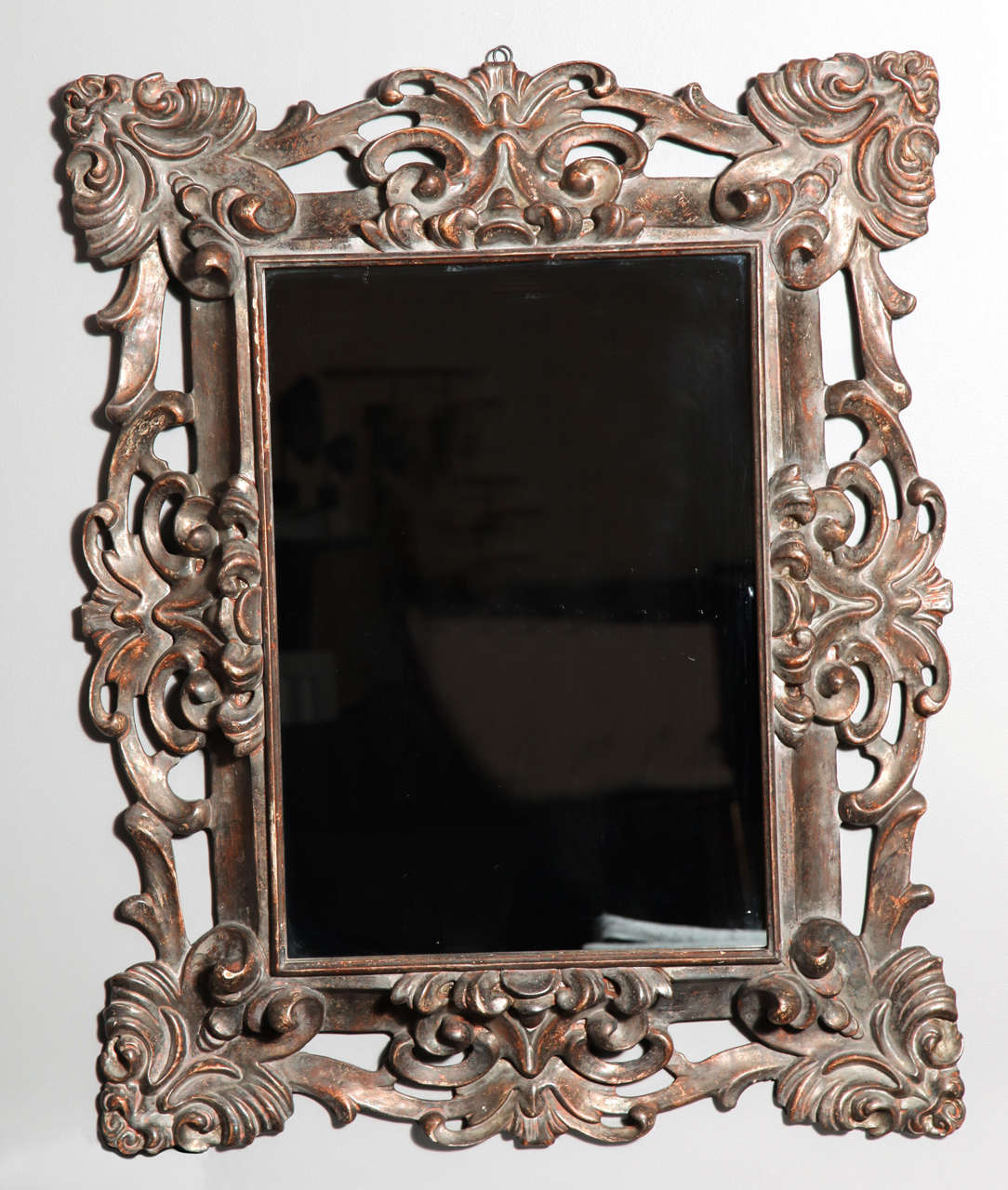 A richly hand-carved frame with openwork floral and foliate design in a distressed silver finish.