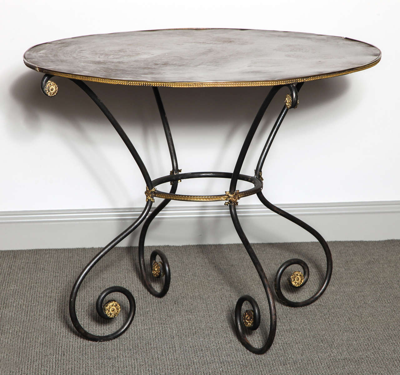 Pair of wrought iron gueridon tables with bronze rosette details and edges, originally found in a private estate outside of Paris.