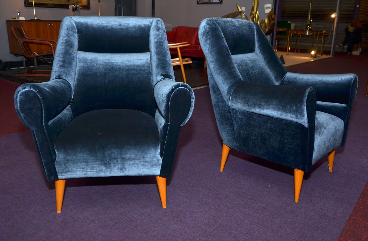 Two 1950s Italian armchairs with wooden legs; reupholstered in dark blue silk velvet with metal studs.