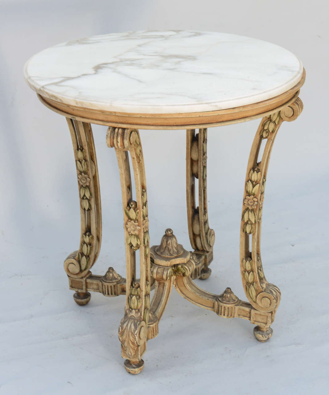 Round accent table, having white veined marble top, raised on molded apron and elaborately carved scrolling legs with rosettes, leafy and acanthus details; connected by stretcher centered by acanthus leaf crown.