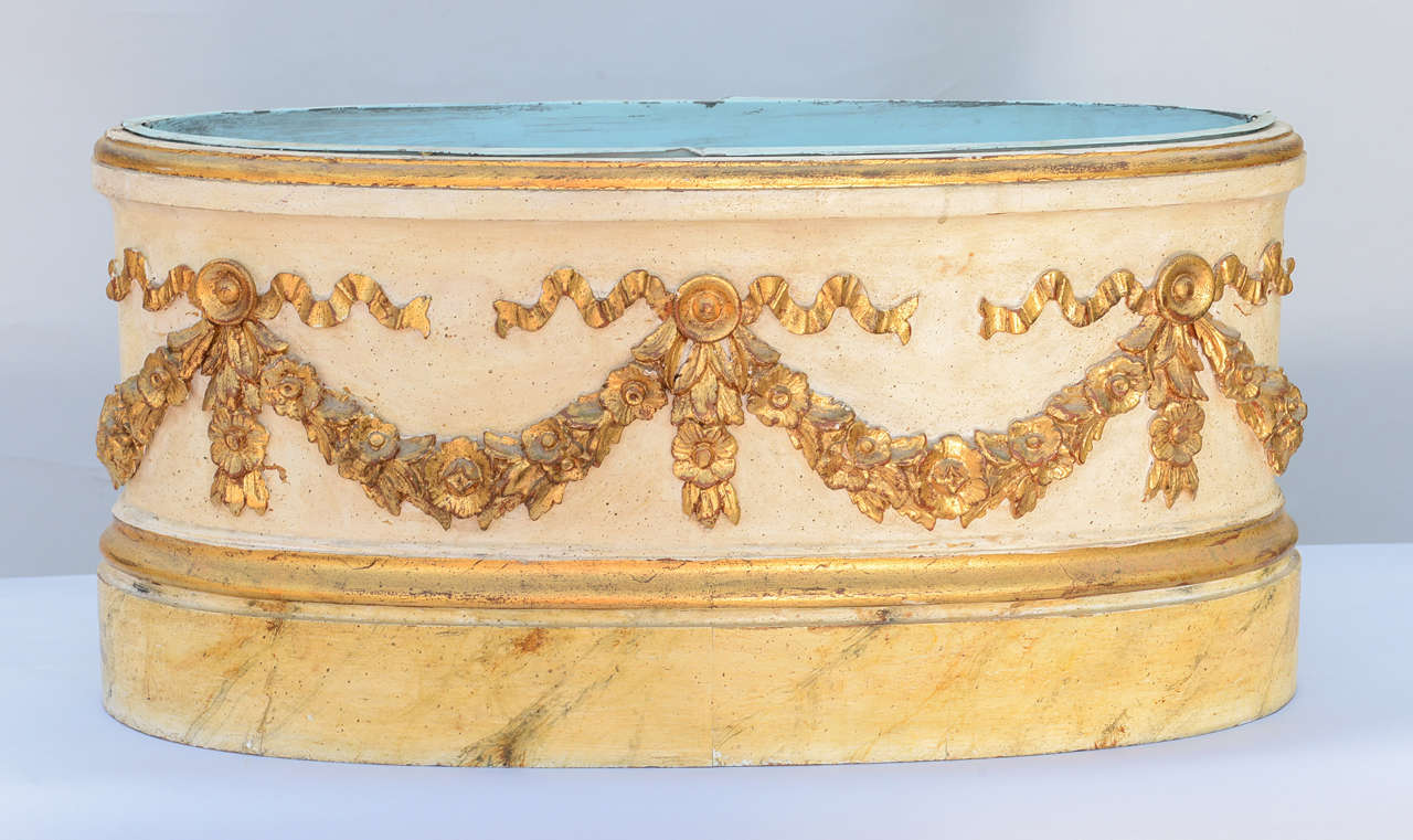 Large oval planter or jardiniere painted and parcel gilt, having wonderfully outcarved floral swags, raised on faux marble base; with original tin liner.
