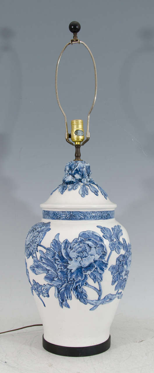 A vintage white ceramic ginger jar table lamp with blue floral motif in relief. 

Good vintage condition with a small chip in ceramic at base of lamp in back above cord.

Reduced from: $1,150