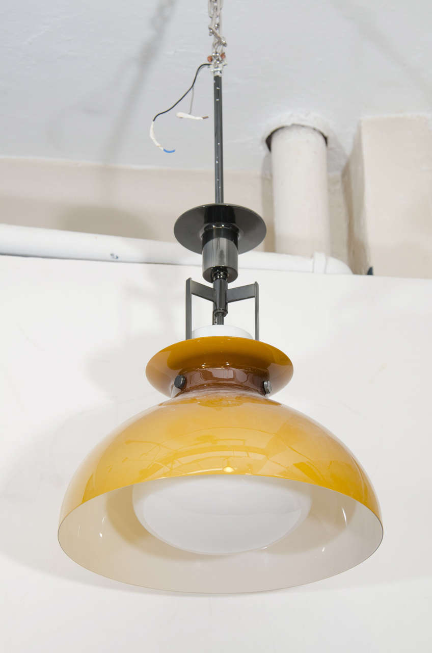 A vintage Italian glass tulip shaped pendant light in a brown color that fades into a pale butterscotch yellow.  A milk white shade covers the bulb.
