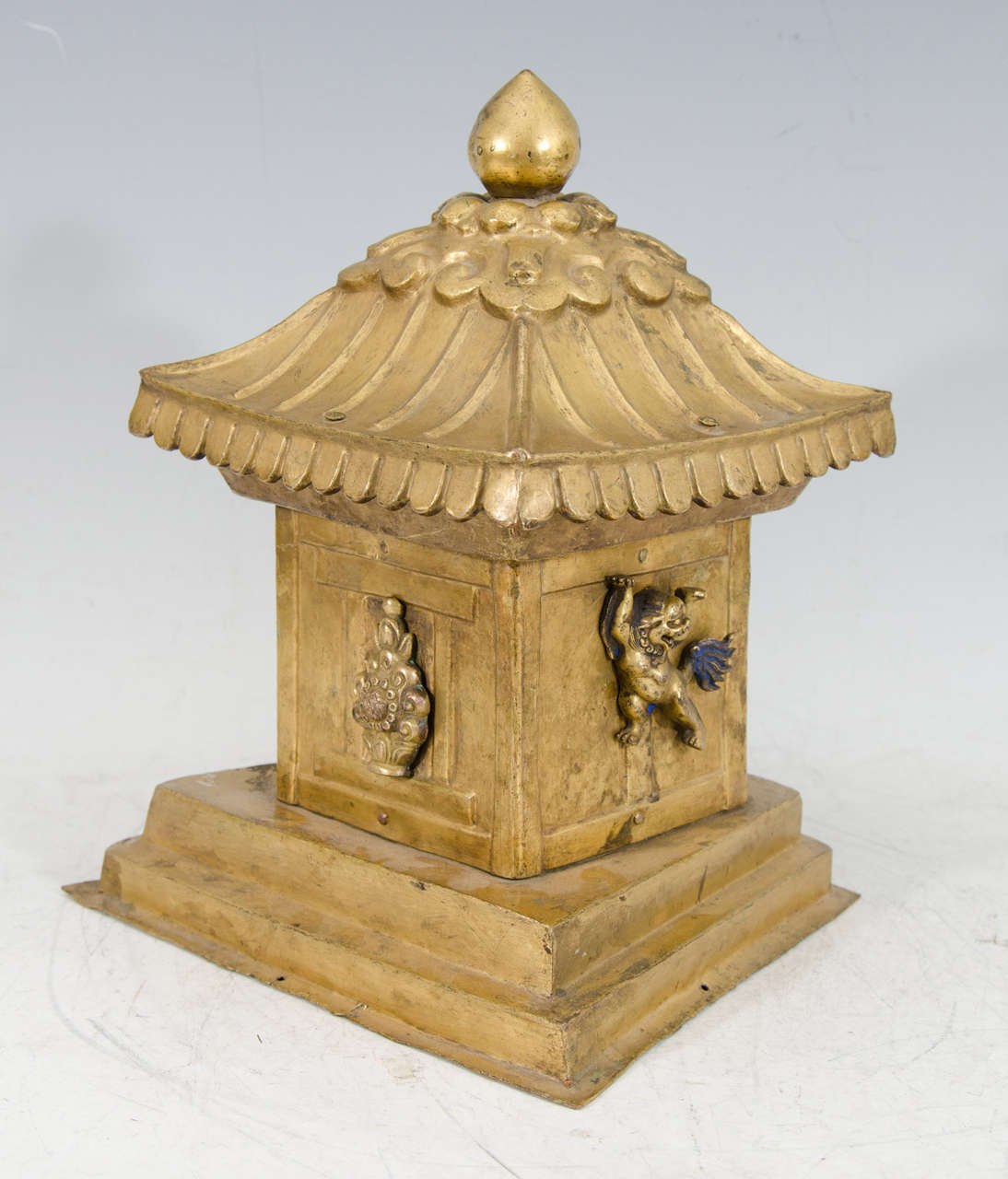 A late 18th or early 19th century Tibetan over-sized architectural gilt bronze reliquary top, shaped like a small temple or stupa. The front is mounted with a floral jewel and the sides have snow leopards raised on their back paws to support the
