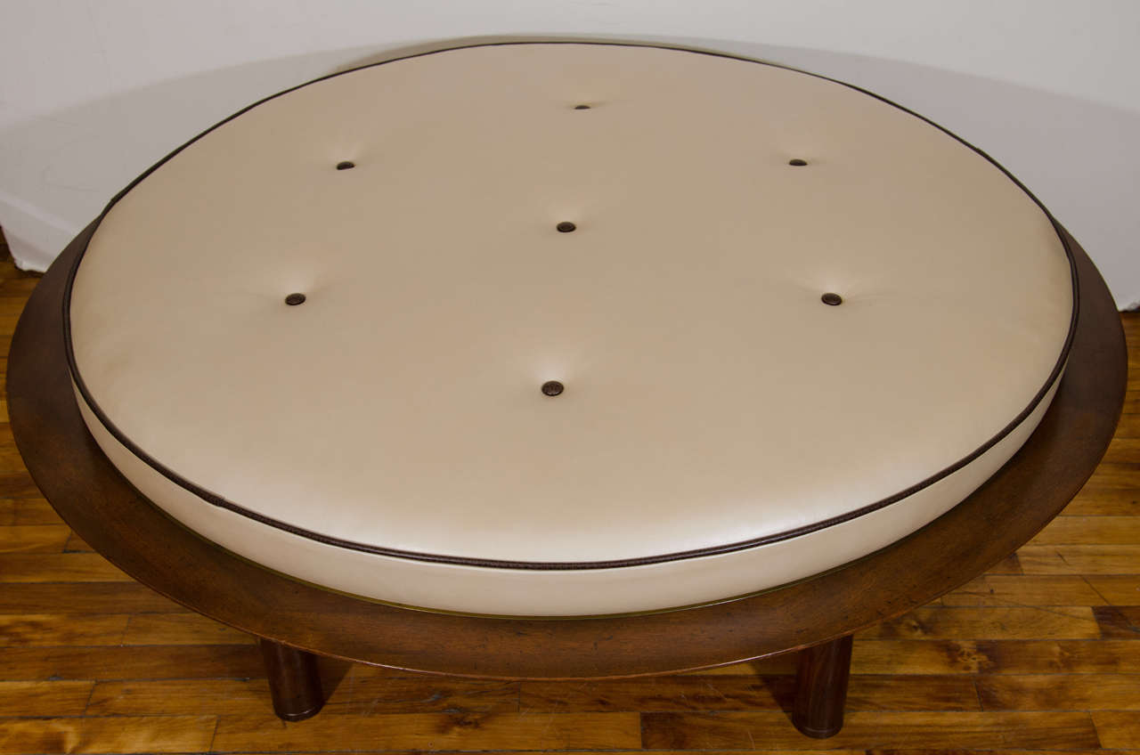 A vintage Danish modern round wooden framed ottoman with brass edging. Newly re-upholsted in a pearlized button tufted leather.

Reduced from: $4,250