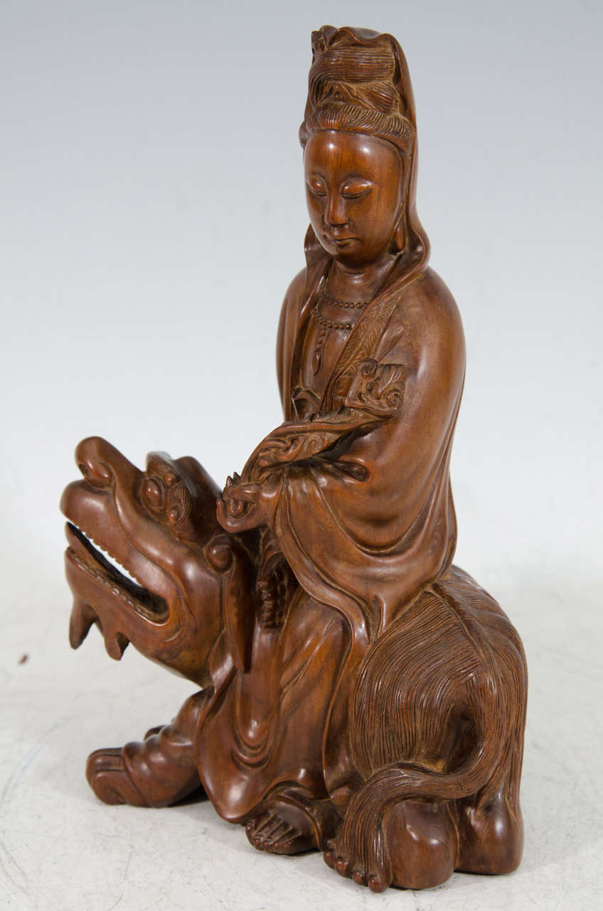A late Qing Dynasty hand carved and polished Asian hardwood Guanyin holding a good-luck ruyi scepter and seated on a mythological beast (probably a Qilin).

Good condition with age appropriate wear.