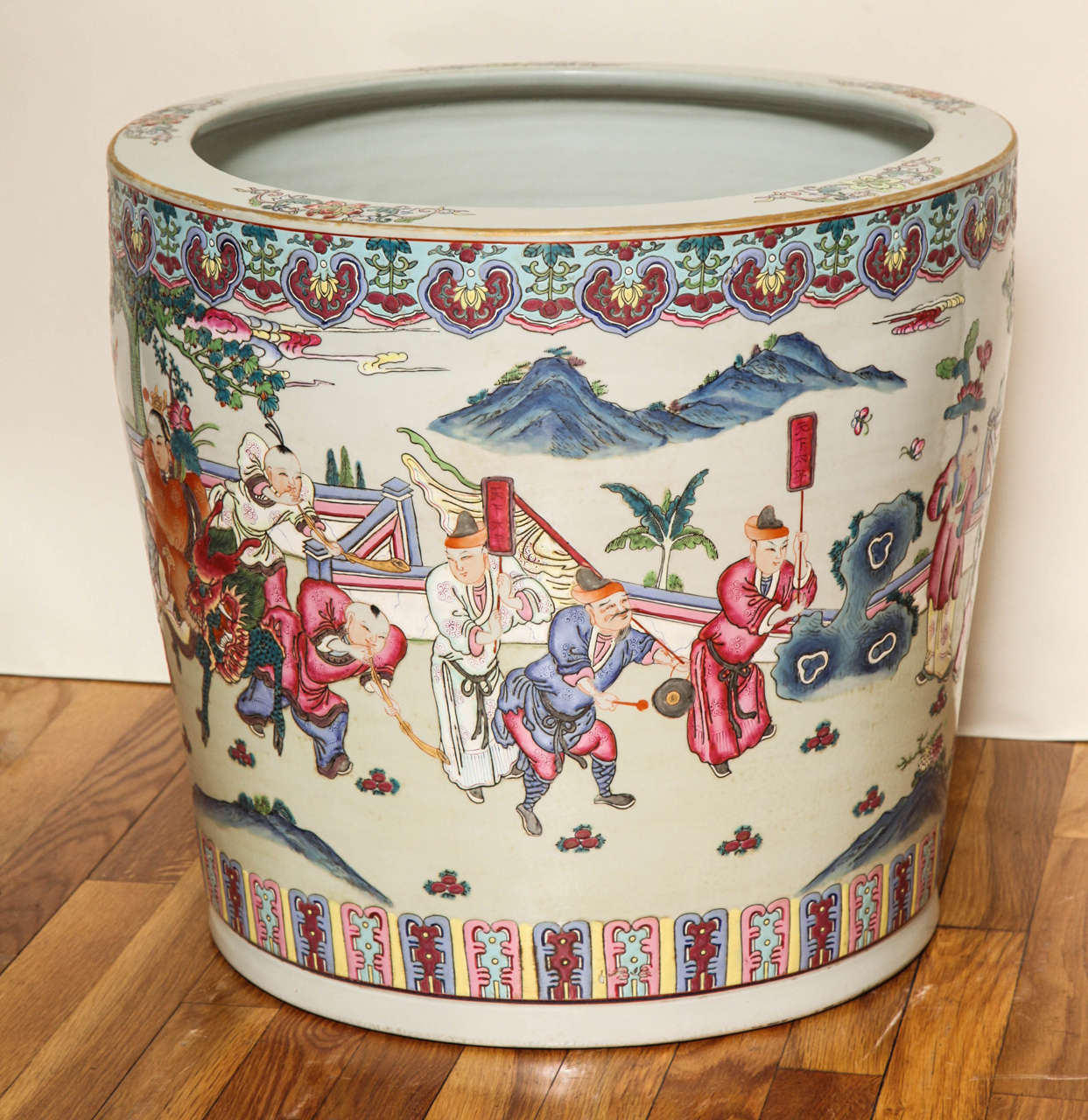 A Chinese porcelain fishbowl with polychrome figures in landscape on an ivory colored ground.