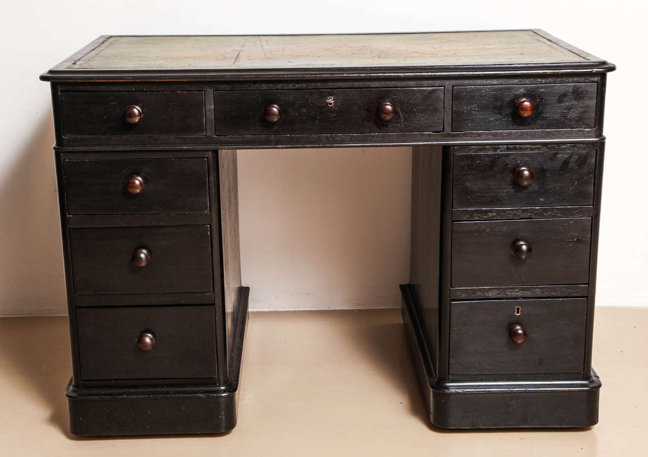 The rectangular green leather-lined top over three frieze drawers above pedestals fitted with three graduated drawers to one side. With wood knobs and on castors. Attractive small-scale.